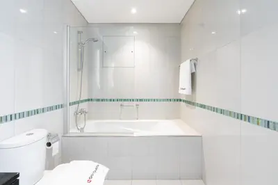 a white bathroom with a tub and a toilet at Gala Guests - Deluxe Marina View Apartments with Infinity Pool in Dubai