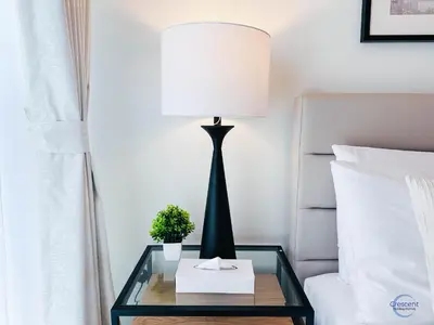 a lamp on a glass table next to a bed at 1BR Downtown Apt Walk to Dubai Mall & Burj in Dubai