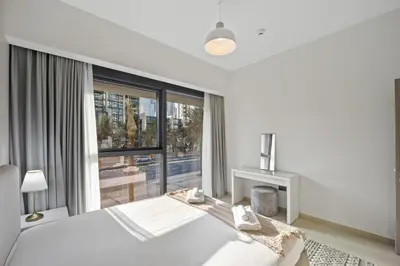 a white bedroom with a bed and a large window at Brand New 1BR Downtown - Next to Dubai Mall in Dubai