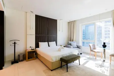 a bedroom with a large bed and a living room at Stylish studio with storage room in hotel l Fits 2 in Dubai