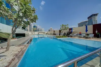 a large swimming pool with blue water in a building at Stylish studio with storage room in hotel l Fits 2 in Dubai