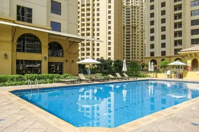 a large swimming pool with chairs and buildings at Vacationer I Premium 3 Bedroom Apartment I Steps Away from JBR Beach in Dubai
