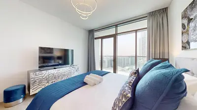 a bedroom with a bed and a large window at Palace Residences - Chic Two Bed with Creek Views in Dubai