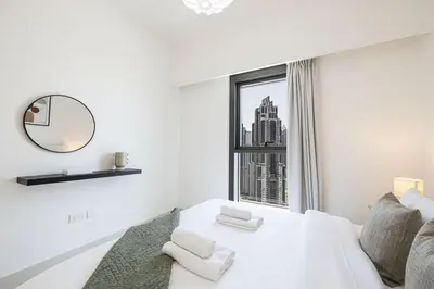 a white room with a window and a bed with towels at LUXE | 2BR | Sea & City View | 5 Min to Dubai Mall in Dubai