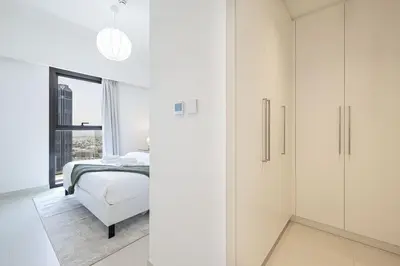 a bedroom with white cabinets and a bed and a window at LUXE | 2BR | Sea & City View | 5 Min to Dubai Mall in Dubai