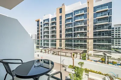 a balcony with a table and chairs and a large building at Stunning 1BR Apartment in Azizi Riviera 42, Al Merkadh by Deluxe Holiday Homes in Dubai