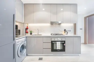 a white kitchen with a stove and a dishwasher at Charming 2BR Home with Elegant Interior in Dubai