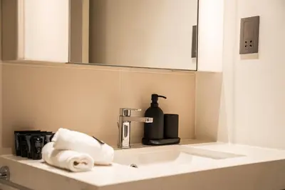 a bathroom sink with a soap dispenser and a towel at SettlerHomes - Seaside Lux Marina near Private Beach in Dubai