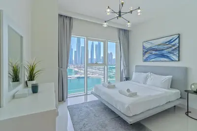 a white bedroom with a large bed and a large window at 2 BR Private Beach Access & Marina View in Dubai