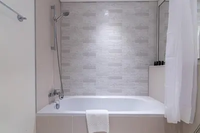 a white bath tub in a bathroom with a shower at 2 BR Private Beach Access & Marina View in Dubai