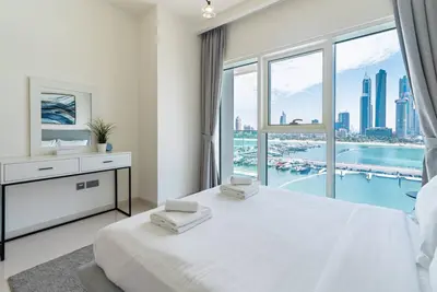a bedroom with a large white bed with a large window at 2 BR Private Beach Access & Marina View in Dubai