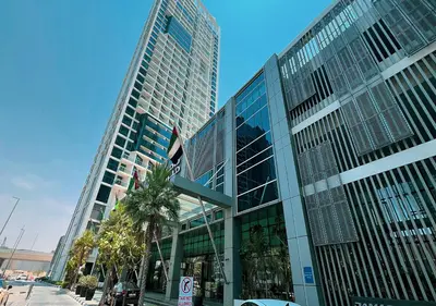 a tall glass building with palm trees in front of it at Lux Studio in Downtown - Damac Maison Prive - Near Burj Khalifa in Dubai