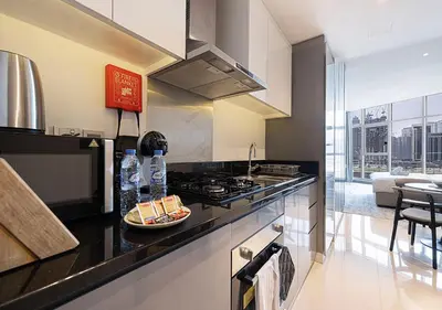 a kitchen with a stove and a plate of food on a counter at Lux Studio in Downtown - Damac Maison Prive - Near Burj Khalifa in Dubai