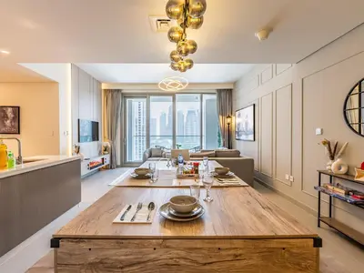 a kitchen and living room with a large wooden table at the London Condo - Forte Downtown Dubai in Dubai