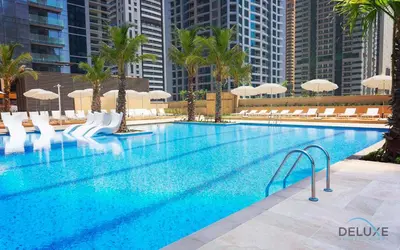 a large swimming pool with chairs and umbrellas at Chic 1BR in The Residence at Marina Gate 2, Dubai Marina by Deluxe Holiday Homes in Dubai