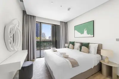 a white bedroom with a large bed and a window at 5 min to Metro - New 1 Bed in Business Bay in Dubai