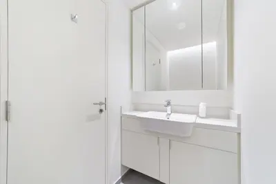 a white bathroom with a sink and a mirror at 5 min to Metro - New 1 Bed in Business Bay in Dubai