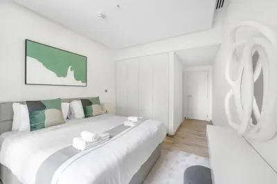 a white bedroom with a large bed and a couch at 5 min to Metro - New 1 Bed in Business Bay in Dubai