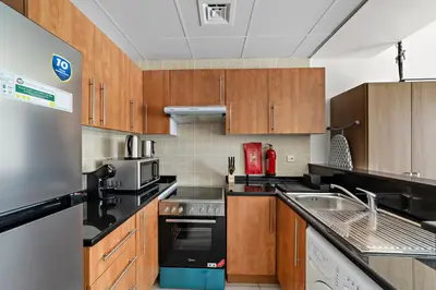 a kitchen with wooden cabinets and stainless steel appliances at StoneTree - Newly Furnished - Near Metro in Dubai