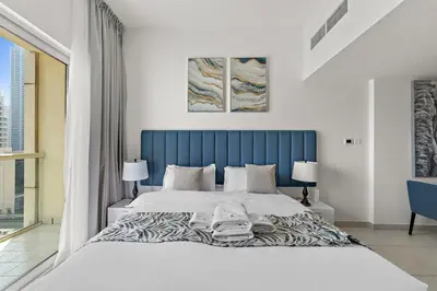 a bedroom with a large bed with a blue headboard at StoneTree - Newly Furnished - Near Metro in Dubai