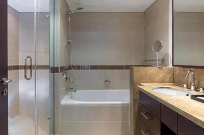a bathroom with a shower and a tub and a sink at Your 2BR with Burj Khalifa View in Dubai