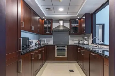 a large kitchen with wooden cabinets and a sink at Your 2BR with Burj Khalifa View in Dubai