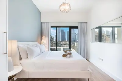 a white bedroom with a bed and a large window at Stunning Renovated Home with Full Burj Khalifa View in Dubai