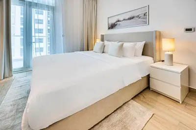 a large white bed in a bedroom with a window at Cozy 2 bedroom apartment in Dubai Marina in Dubai