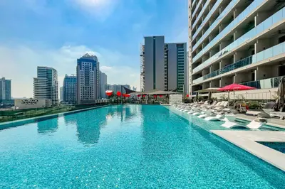 a swimming pool with chairs and umbrellas in a city at Studio MAG 318 City View Business Bay in Dubai