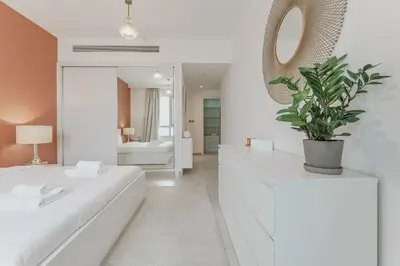 a white room with two beds and a mirror at Prime Downtown 2BR Retreat in Dubai