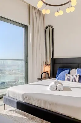 a bedroom with a large bed with a large window at Sobha waves I Cozy 1BDR I Burj Khalifa View in Dubai