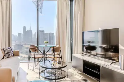 a living room with a table and a large window at Sobha waves I Cozy 1BDR I Burj Khalifa View in Dubai