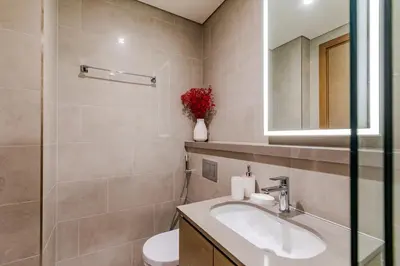 a bathroom with a sink and a toilet and a mirror at Sobha waves I Cozy 1BDR I Burj Khalifa View in Dubai