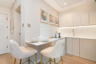 a kitchen with two white chairs and a table at Upgraded Designer-crafted Studio in JVC with Massive Terrace in Dubai