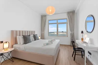 a white bedroom with a bed and a desk at Exquisite 1BR with Private beach in Palm Jumeirah in Dubai