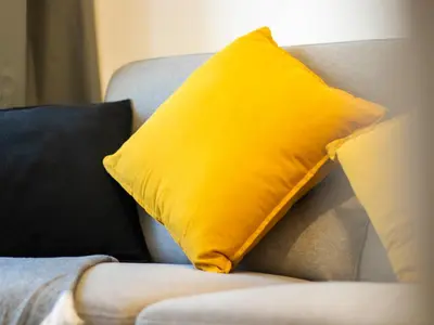 a yellow pillow sitting on top of a couch at Spacious 2BR with Big Balcony In Meydan in Dubai