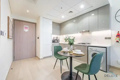 a kitchen with a table and green chairs at Delightful 1BR Apartment in Azizi Riviera 22, Al Merkadh by Deluxe Holiday Homes in Dubai