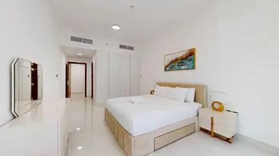 a white bedroom with a bed and a television at Locations I Uni Estate Supreme Residence I Luxury 1BR I Near Miracle Garden I Pool, Gym & Parking in Dubai