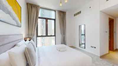 a white bedroom with a large white bed with windows at Liv Residences - Spacious Two Bedroom in Dubai