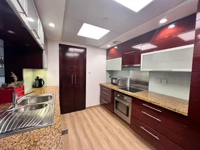 a kitchen with wooden cabinets and stainless steel appliances at Luxurious 1BR in Burj Views Podium, Downtown in Dubai