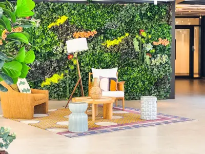 a living room with a table and chairs in front of a green wall at Socio Tower1 - Dubai Hills Modern Urban Retreat in the City by Serenity Living Holiday Homes in Dubai