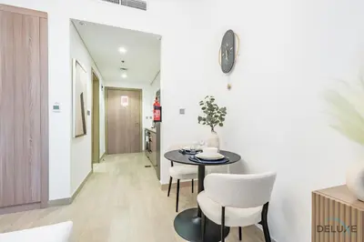a dining room with a table and white chairs at Stylish Studio Apartment in Azizi Riviera 37 Al Merkadh by Deluxe Holiday Homes in Dubai