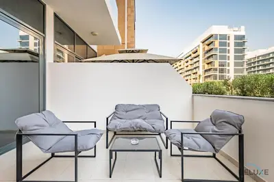 two chairs and a table on a balcony at Stylish Studio Apartment in Azizi Riviera 37 Al Merkadh by Deluxe Holiday Homes in Dubai
