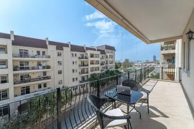 a balcony with chairs and a table with a laptop on it at Peaceful flat in Motor City in Dubai
