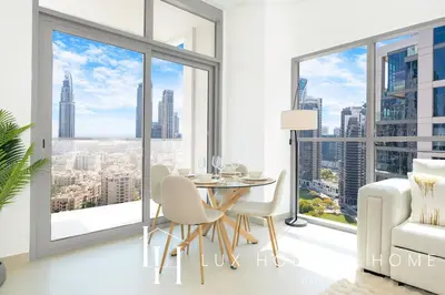 a dining room with a table and chairs and large windows at LUX The Executive Burj Khalifa View Suite in Dubai