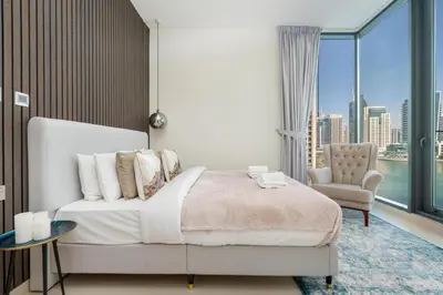 a bedroom with a bed and a chair and a window at Vacay Lettings - Liv Residence in Dubai