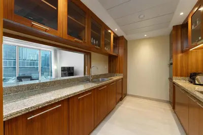 a kitchen with wooden cabinets and a large window at Maison Privee - Cosmopolitan Apt with Scenic Dubai Marina Vws in Dubai