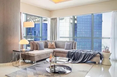 a living room with a couch and a large window at Manzil - 1BR Apt with Pool close to Downtown in Dubai