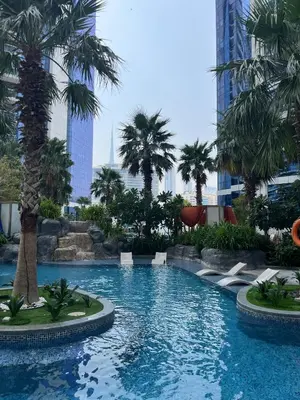 a large swimming pool with palm trees in a city at Manzil - 1BR Apt with Pool close to Downtown in Dubai