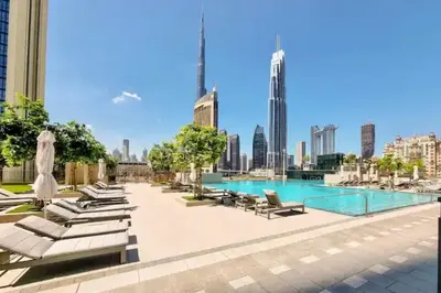 a swimming pool with lounge chairs and a city skyline at New Stunning 4 BR Burj Khalifa View in Dubai